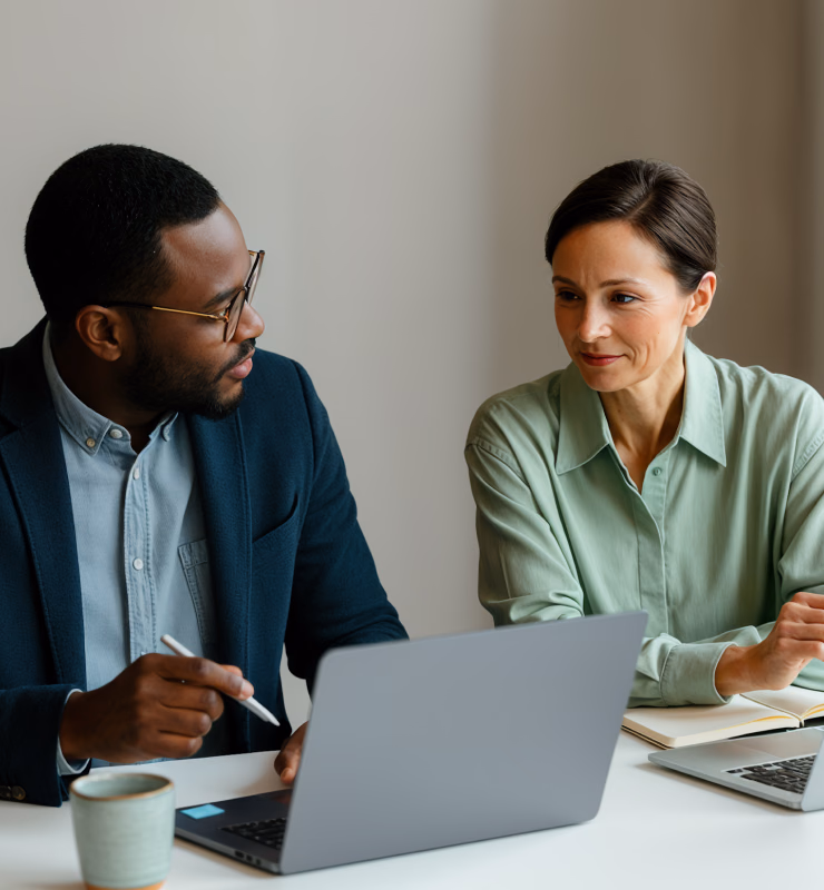 Two colleagues reviewing documents on a laptop